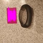 Preview thumbnail for Handheld strainer/press-like object. Curved metal with holes, black plastic handle. ~debit card length, 2cm width. Found in kitchen